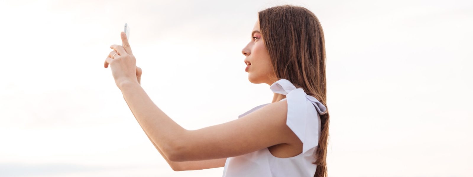 Woman standing and talking selfie with smartphone outdoors