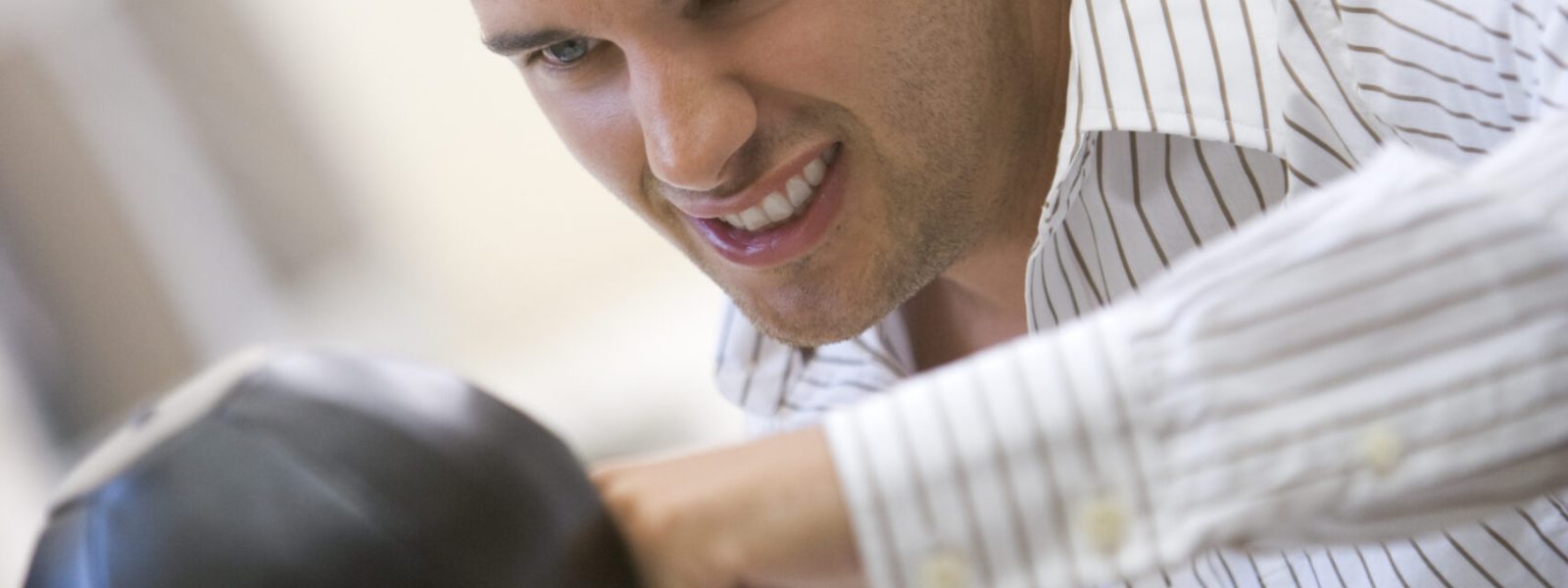 Man sitting in computer room using small punching bag for stress